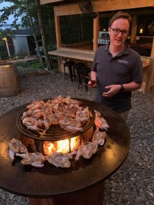 Stephen cooks a large batch of chicken at an outdoor kitchen at dusk. 