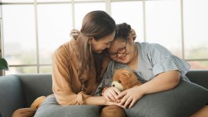 Mother sitting with smiling down syndrome daughter