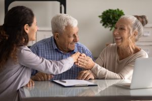 Happy senior couple of clients meeting with real estate or insurance agent, shaking hands with realtor, broker, thanking lawyer for consultation, help with document filling, giving handshake